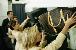 Travelers-putting-their-carry-on-luggage-in-the-overhead-compartment
