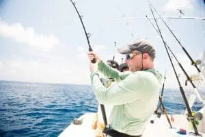 a person on a fishing boat reeling in a large fish